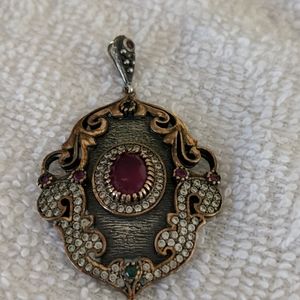 Gold tone and silver pendant with red stone